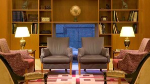 Una biblioteca con dos sillones, un globo terráqueo y estanterías.