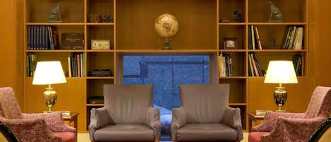 A library with two armchairs, a globe, and bookshelves.
