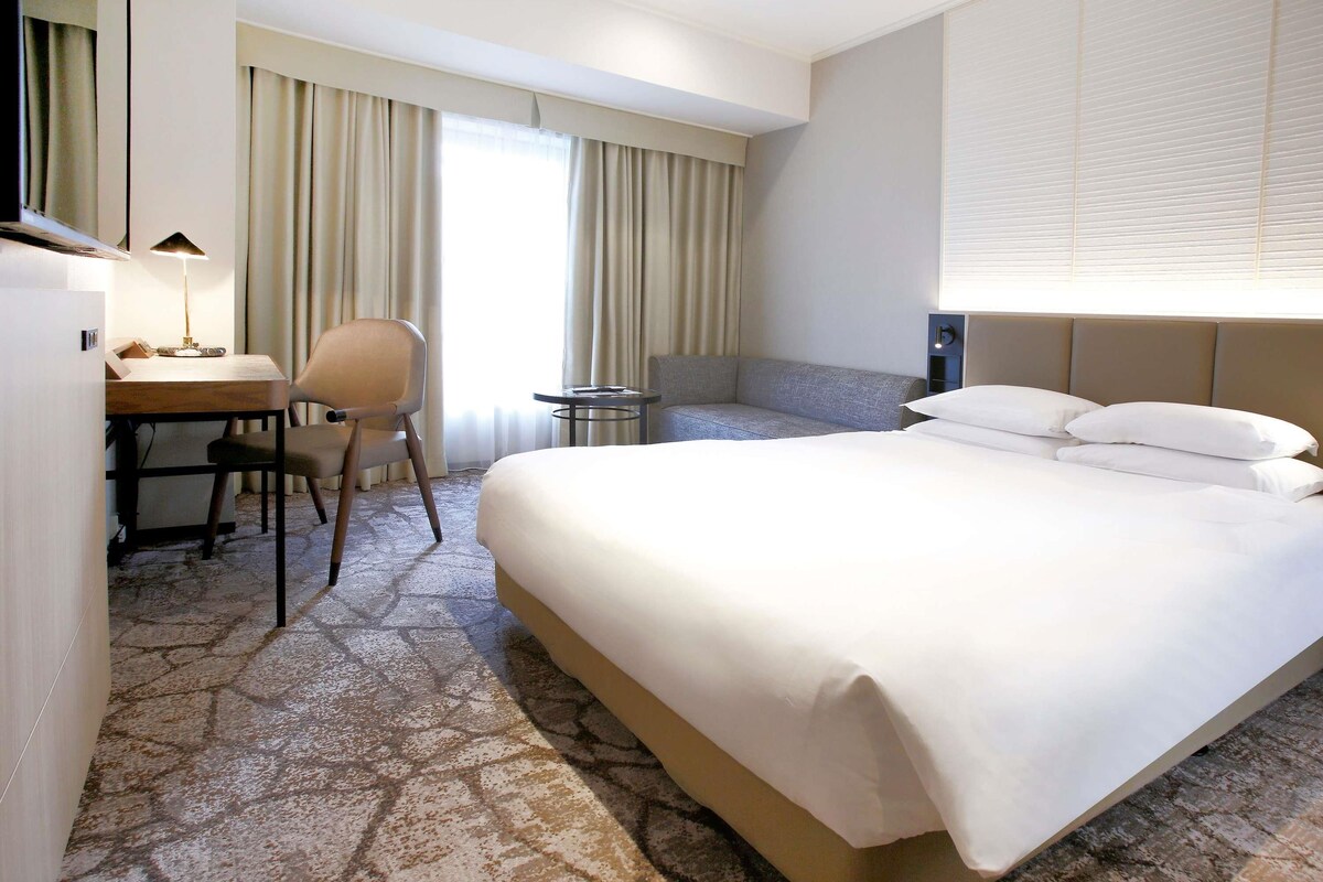 Ein Hotelzimmer mit Bett, Schreibtisch, Stuhl und einem kleinen Tisch.