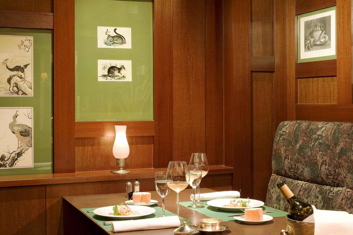 Un coin repas avec une table dressée pour deux personnes, comprenant des assiettes de nourriture, des verres à vin et une bouteille de champagne.