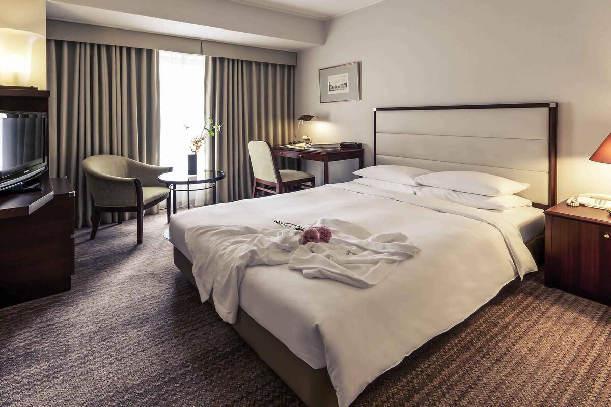 Ein Hotelzimmer mit einem Bett, einem Schreibtisch, einem Sessel, einem Fernseher und einer Lampe.