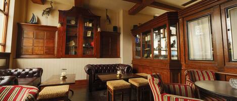 A traditional room with a wooden bench, striped chairs, and a table with a lamp.