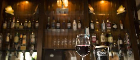 A bar with a glass of red wine and a Guinness beer glass.