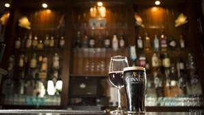 Una barra con un vaso de Guinness y un vaso de vino sobre el mostrador.