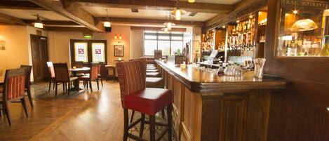A bar area with wooden furniture, a bar counter, and hanging lights.