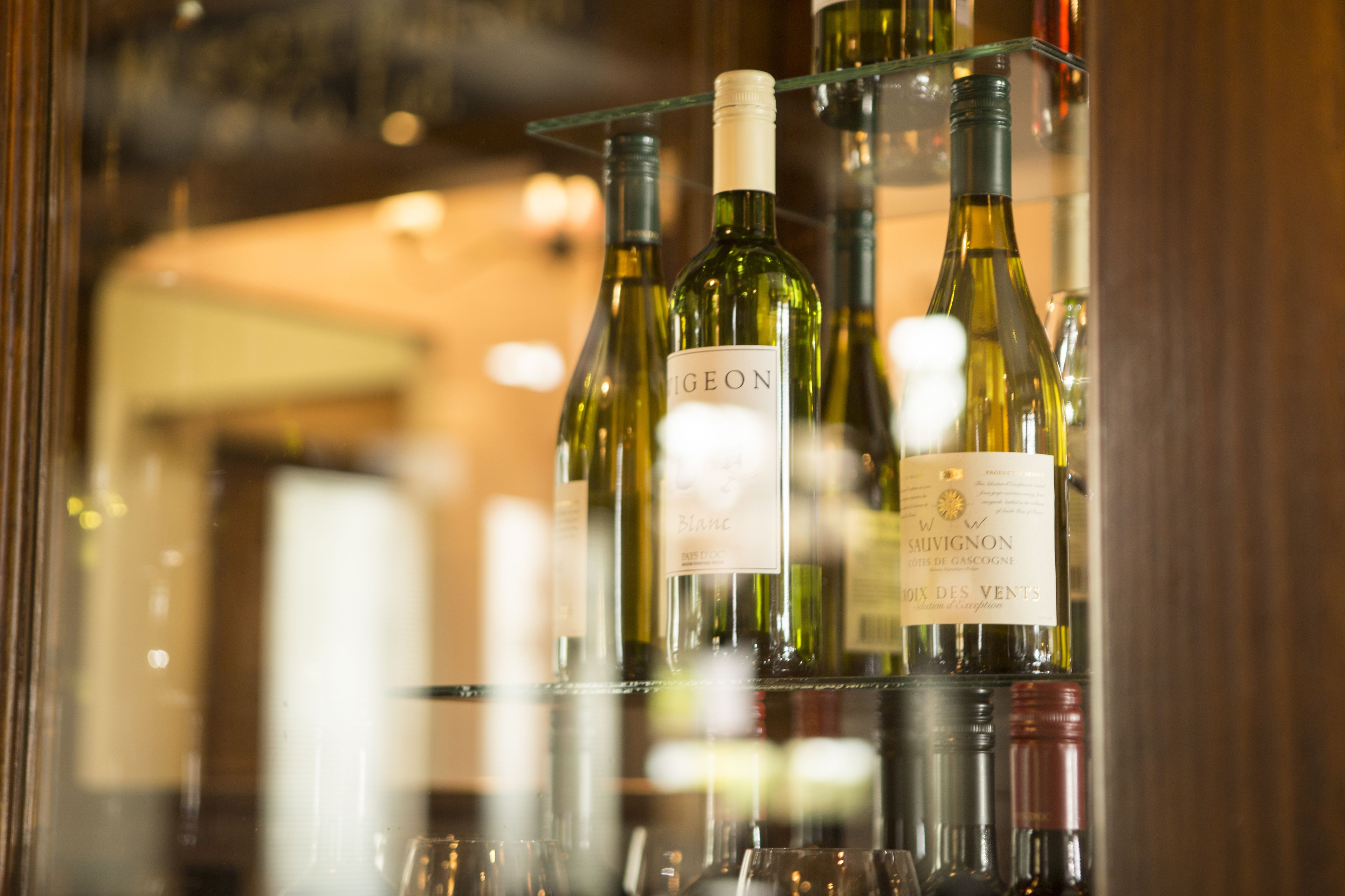 A selection of wine bottles on a glass shelf, with labels visible.