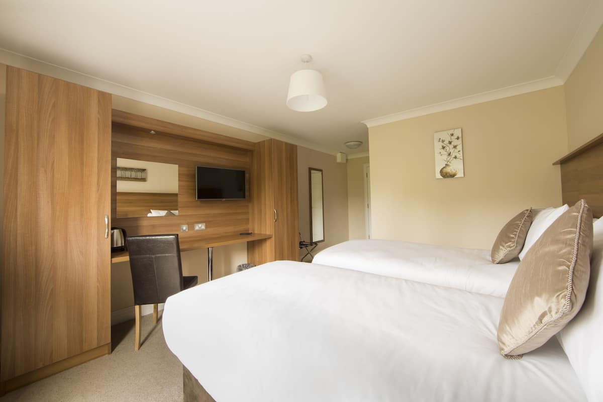 Una habitación de hotel con cama, escritorio, silla y televisión.