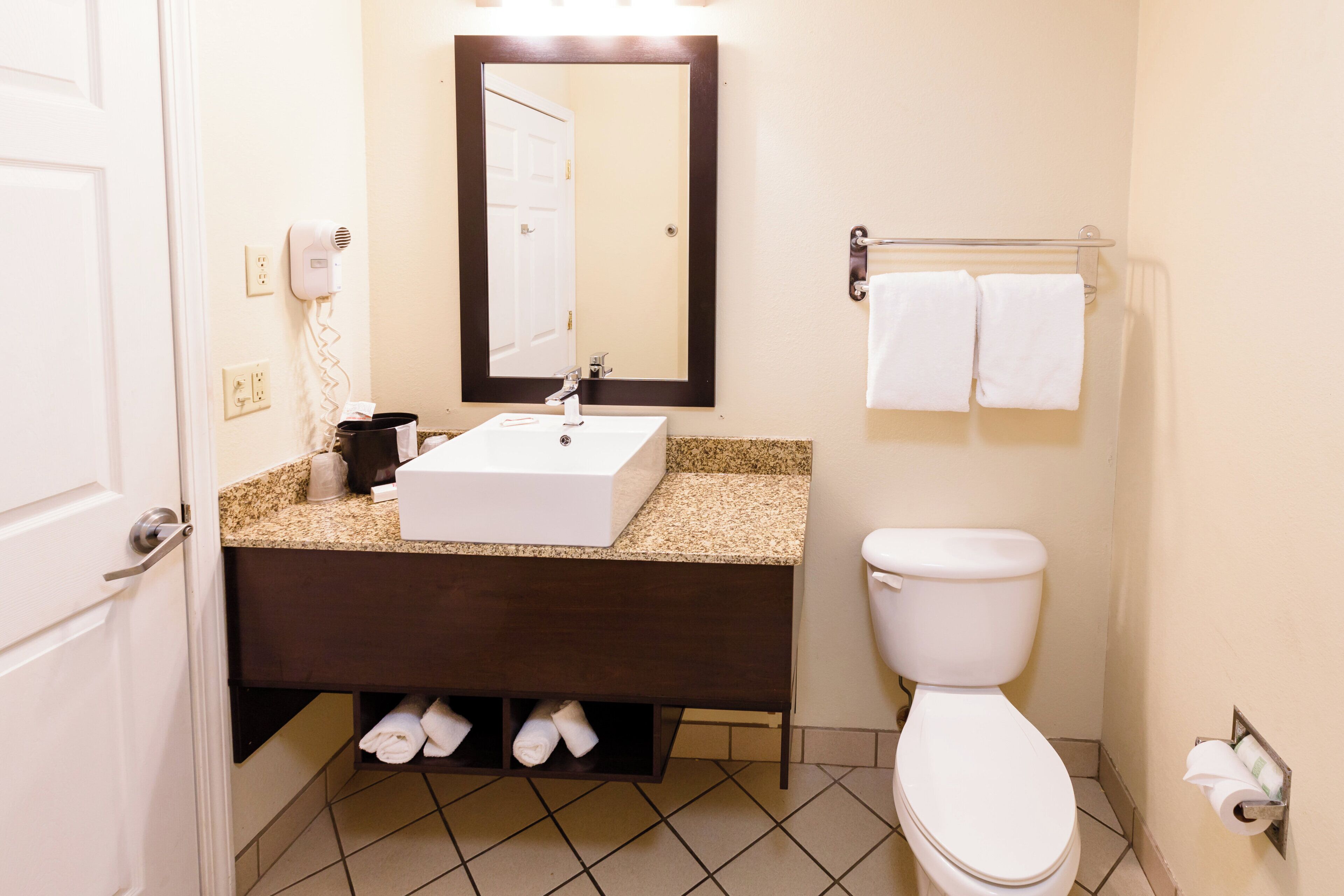 A bathroom with a white sink, a mirror, a toilet, and a towel rack.