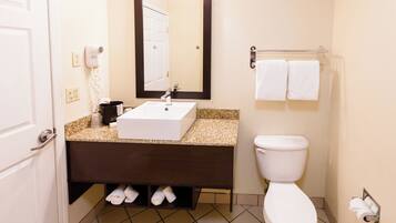 A bathroom with a white sink, a mirror, a toilet, and a towel rack.