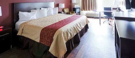 Habitación de hotel con cama, mesitas de noche, escritorio, silla, televisor y ventana con cortinas.