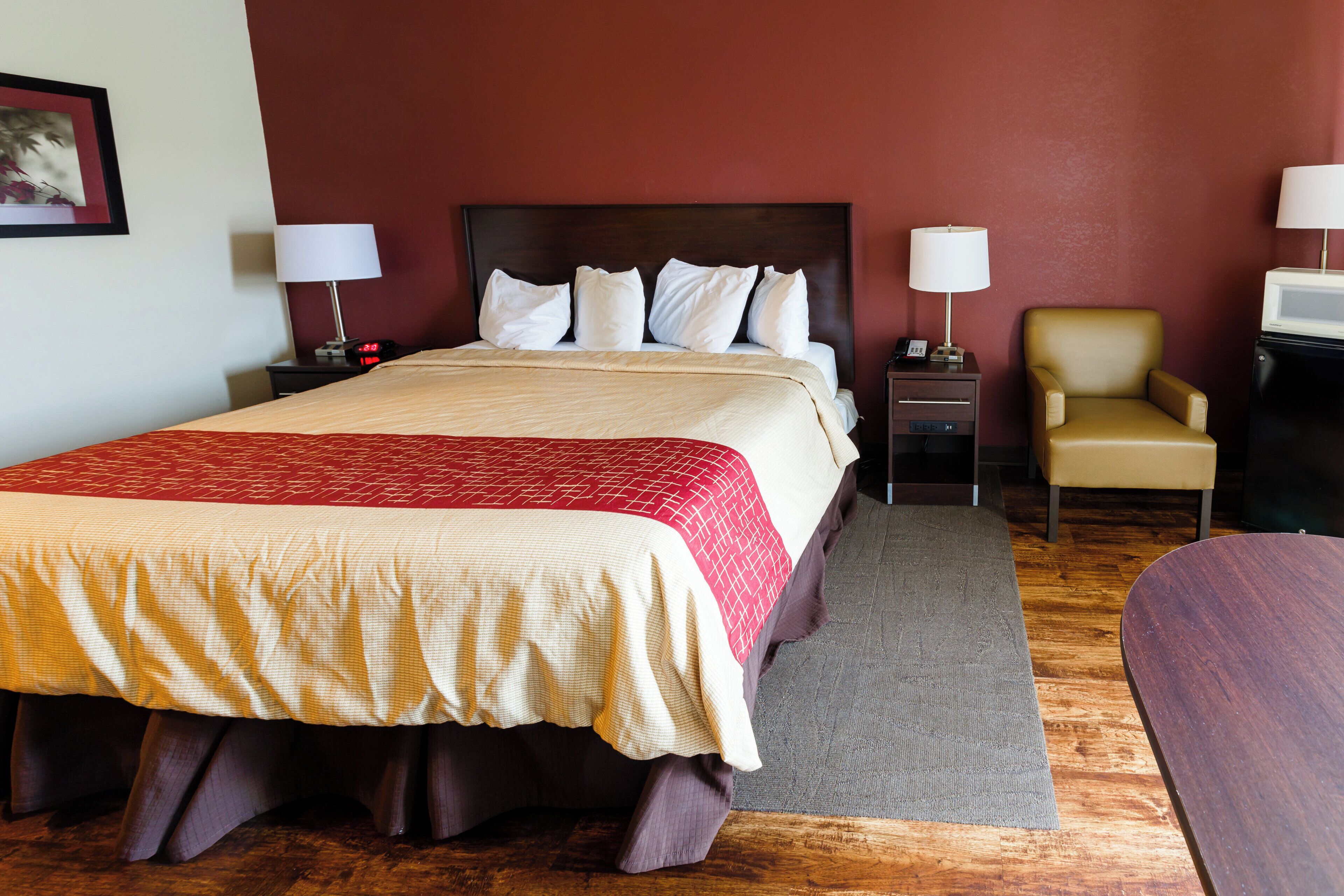 A hotel room with a bed, bedside tables, a chair, a desk, and a television.