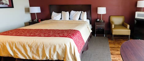 A hotel room with a bed, bedside tables, a chair, a desk, and a television.