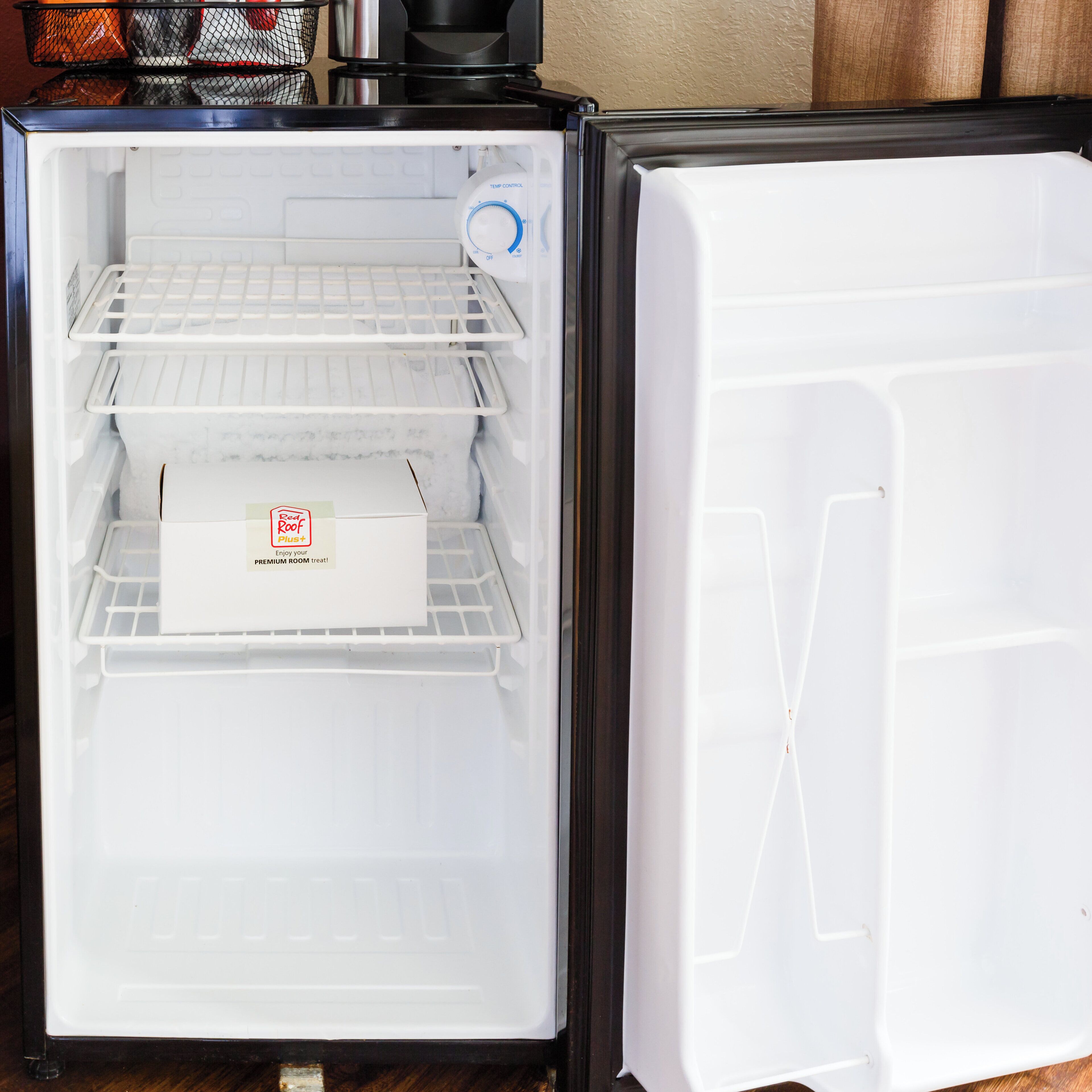 An open refrigerator with multiple shelves and a temperature control dial.