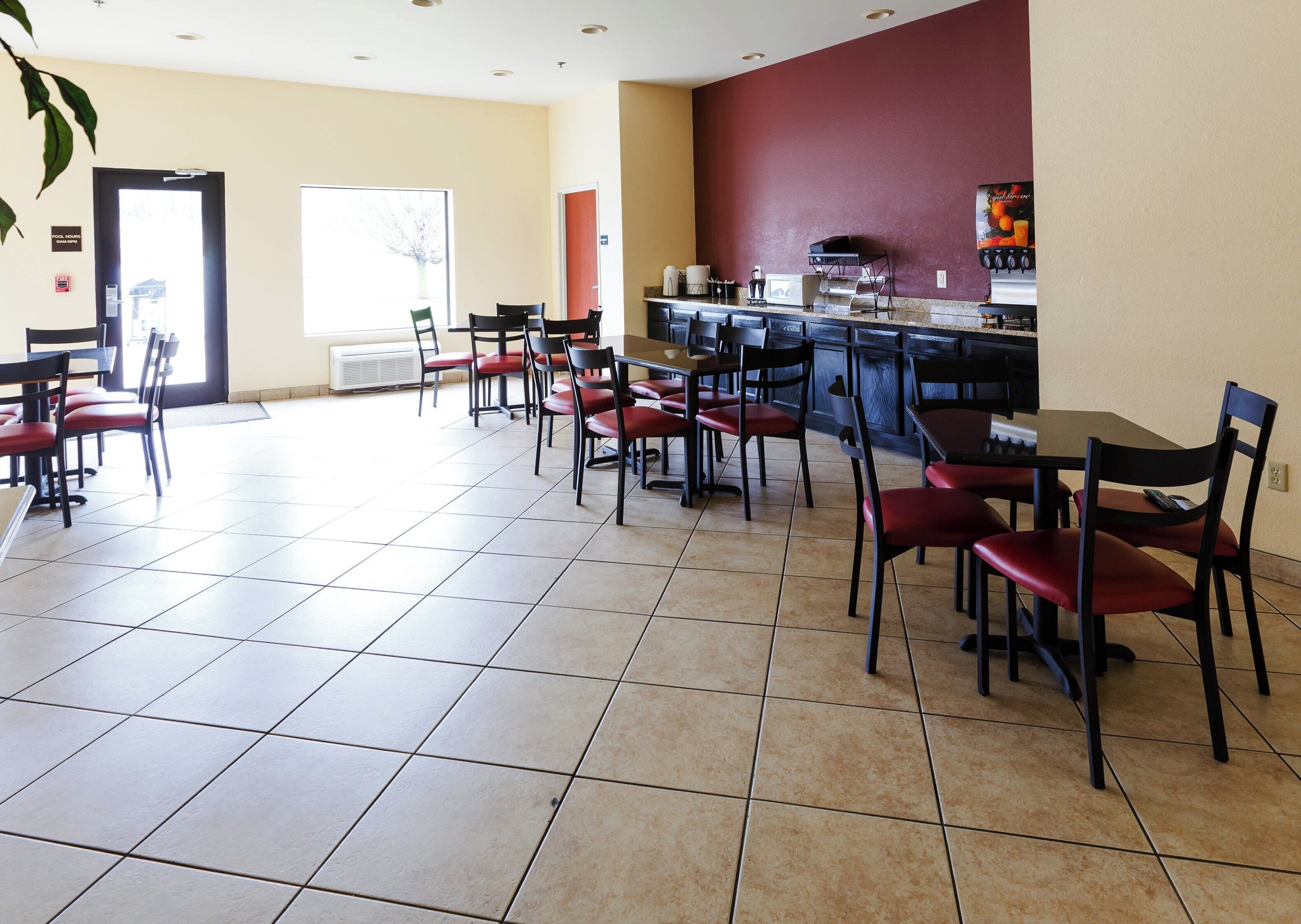 Un restaurante con barra, varias mesas y sillas, y piso de baldosas.