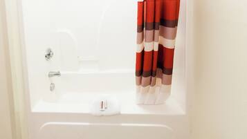 A white bathtub with a shower head, a towel, and a striped shower curtain.