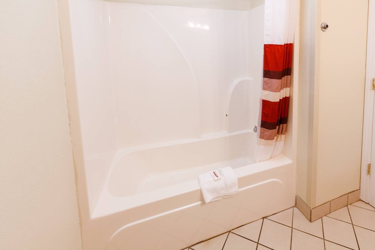 Un baño con una bañera blanca, una cortina de ducha y una toalla colgada en la pared.