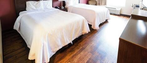 Una habitación de hotel con dos camas, un escritorio y una ventana con cortinas.