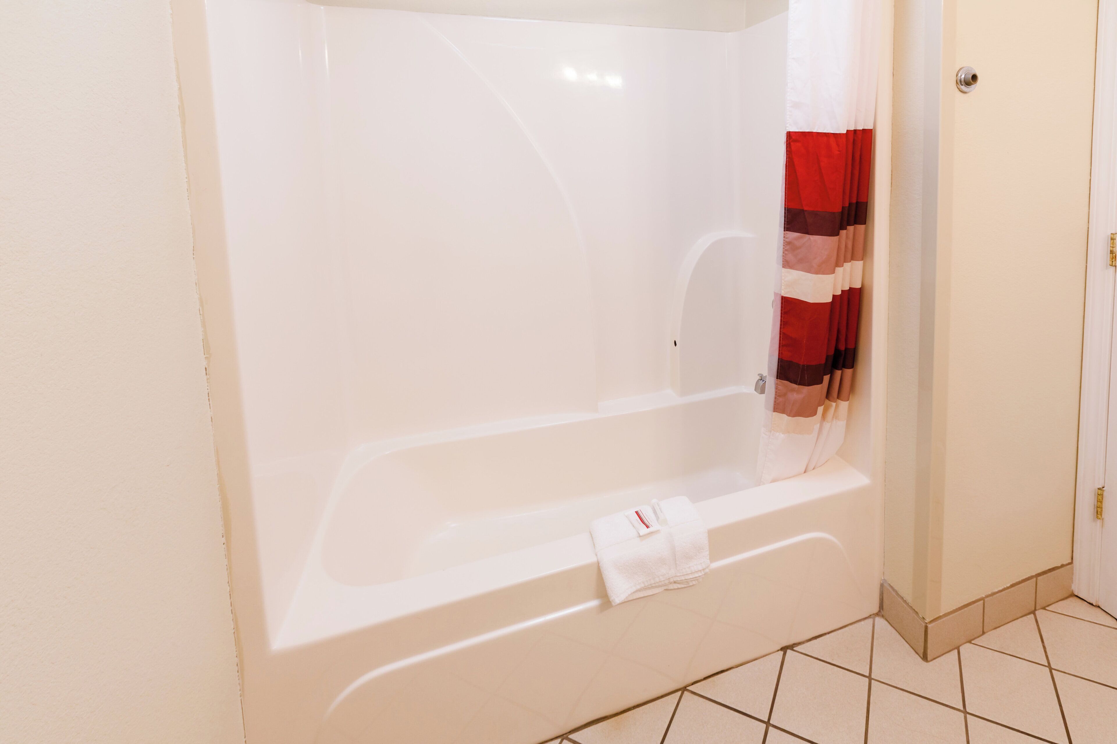 Un baño con una bañera, un cortinón de ducha y una toalla sobre la bañera.
