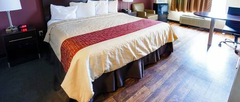 Habitación de hotel con una cama grande, mesitas de noche, un escritorio, una silla y una ventana con cortinas.