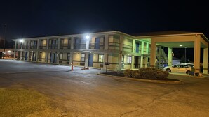A motel with a two-story structure, a covered parking area, and a car parked inside.