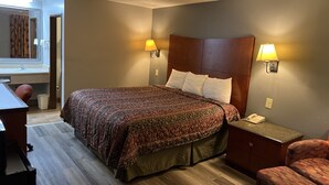 A hotel room with a large bed, bedside lamps, a desk, and a chair.