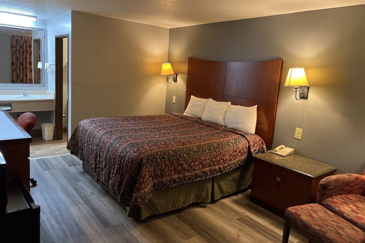 Une chambre d’hôtel avec un grand lit, des lampes de chevet, un bureau et une chaise.