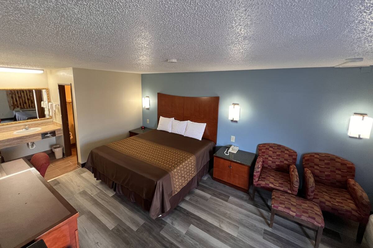 Une chambre d’hôtel comprenant un lit, un bureau, une chaise, une table de chevet et un miroir.