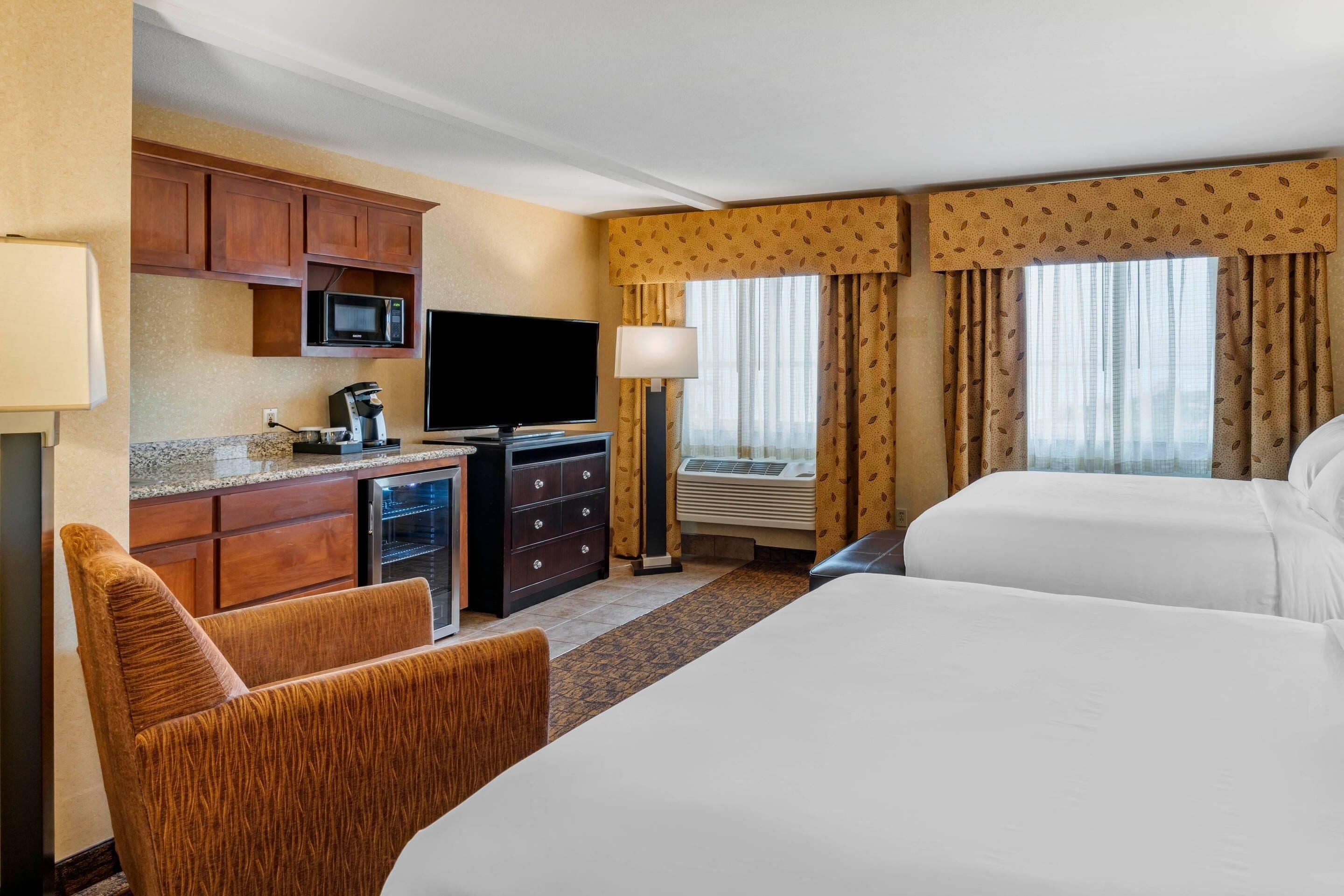 A hotel room with a bed, a desk with a television, a microwave, and a coffee maker.