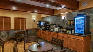 Habitación de hotel con zona de comedor de madera, refrigerador y cafetera.