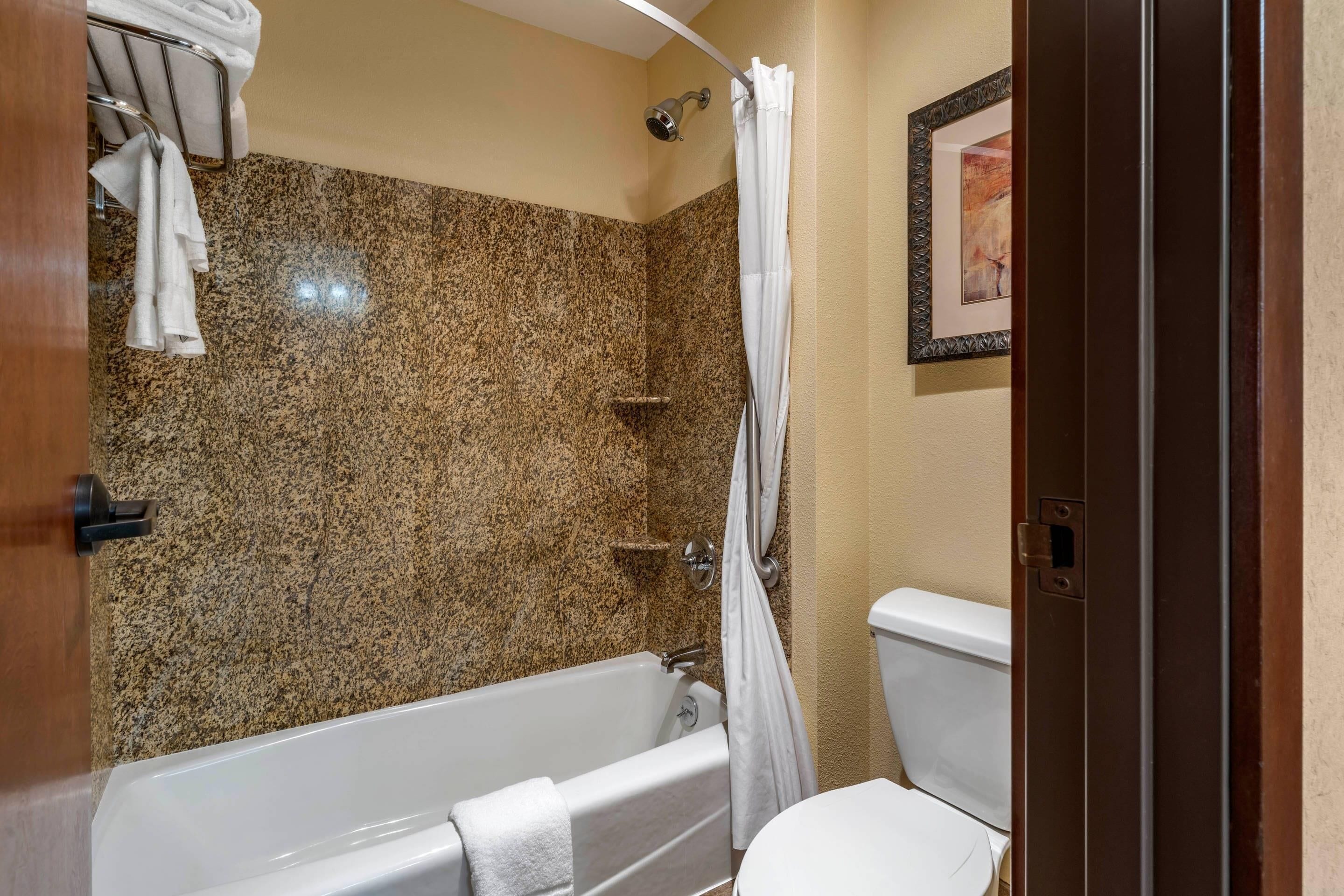 Een badkamer met een bad, douchegordijn, toilet en handdoekhouder.