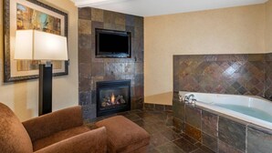 Un baño moderno con chimenea, una bañera grande y un televisor de pantalla plana montado en la pared.