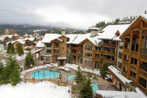 A resort with multiple wooden buildings, a central pool area, and snowy surroundings. - First Tracks Lodge, by Lodging Ovations (Whistler)