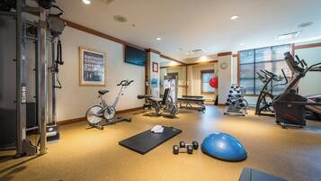 A gym with exercise equipment, a yoga mat, and dumbbells.