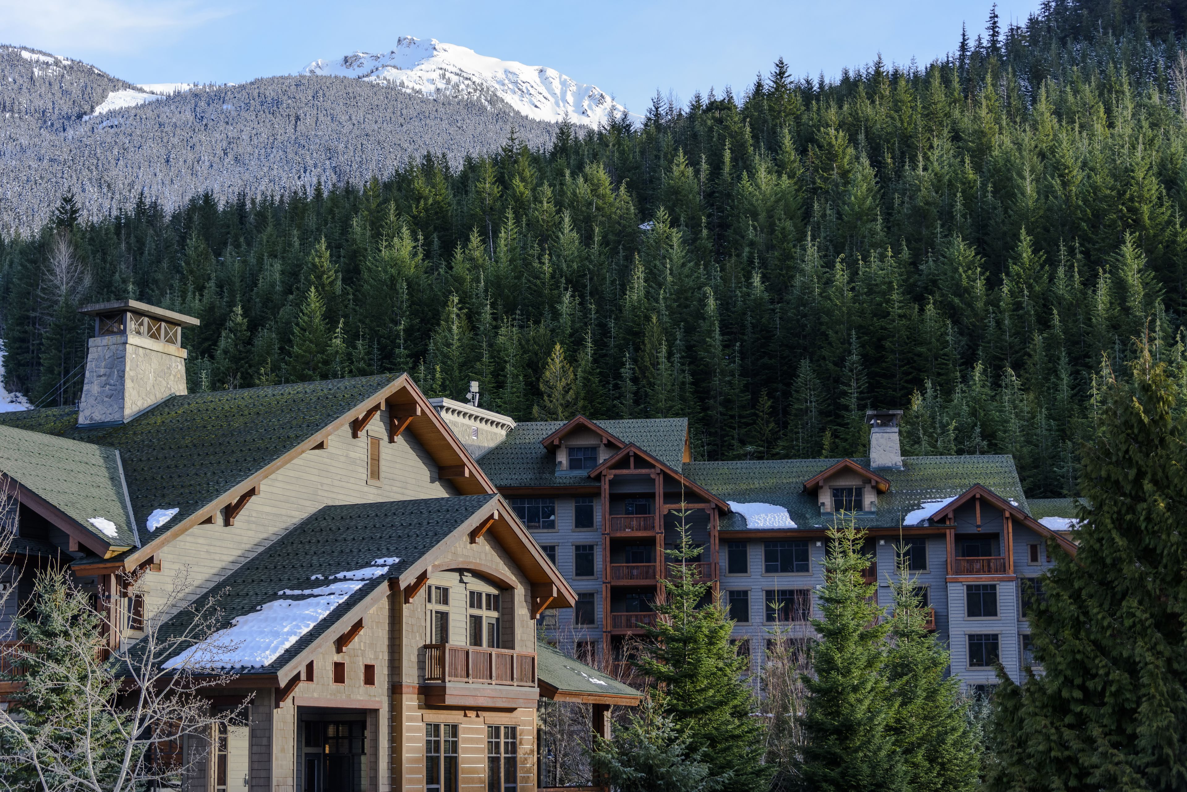 A lodge with multiple buildings, wooden balconies, and a mountainous backdrop.