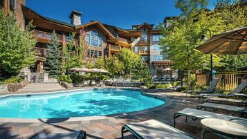 A pool area with lounge chairs and a stone staircase leading to a building.