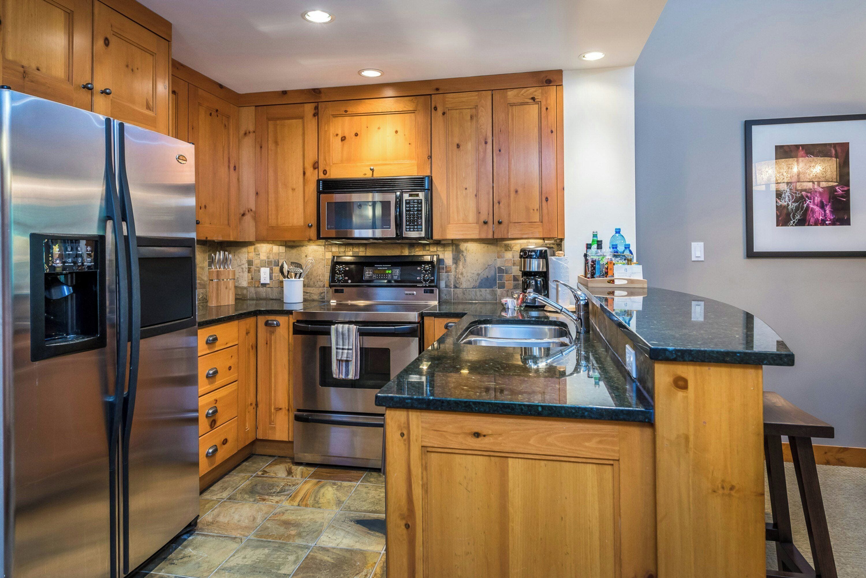 A modern kitchen with wooden cabinets, stainless steel appliances, and a granite countertop.