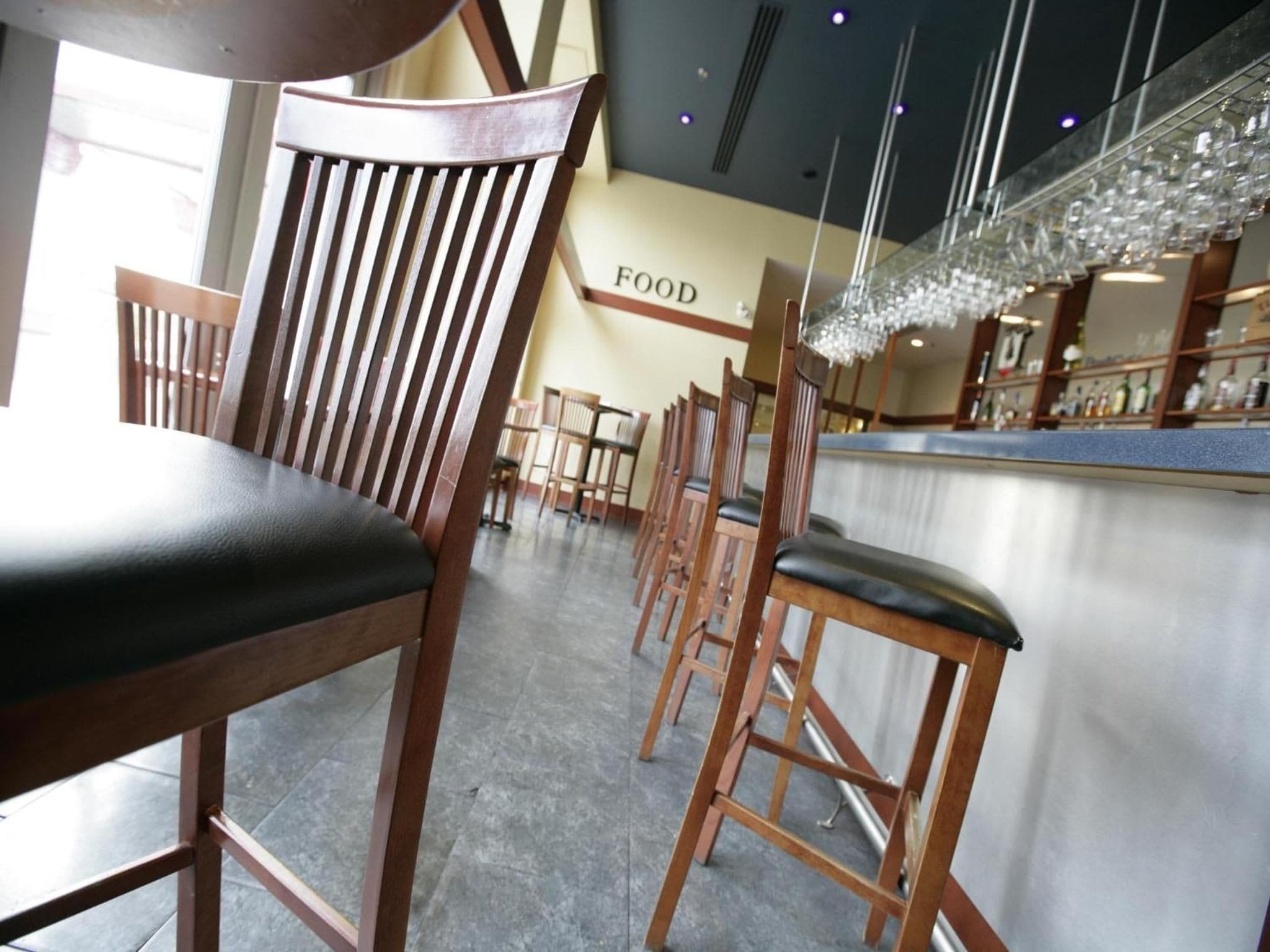 A restaurant interior with wooden chairs and a bar area.
