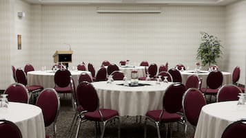A conference room with round tables, red chairs, and a podium.