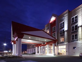 A hotel with a gas station attached, featuring a red and white color scheme, multiple floors, and a prominent sign.