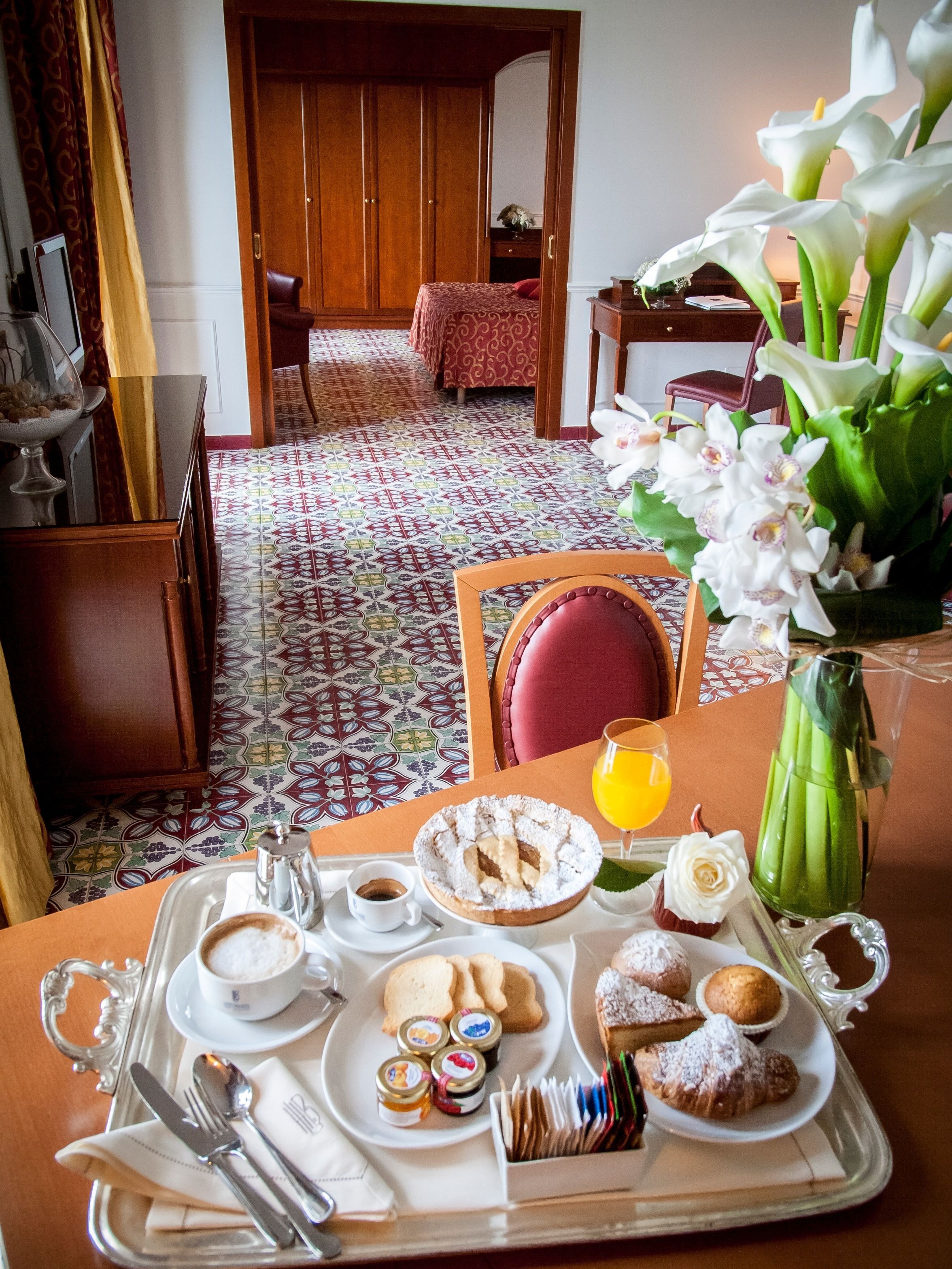 A breakfast tray with pastries, a coffee cup, and a glass of orange juice.