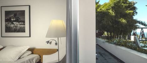 A modern hotel room with a bed, a desk, a lamp, and a framed picture on the wall.