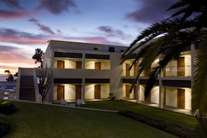 A modern hotel with a two-story structure, multiple balconies, and a well-maintained lawn.