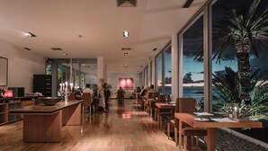 Un restaurante moderno con una barra alargada, suelo de madera y amplios ventanales con vistas al océano.