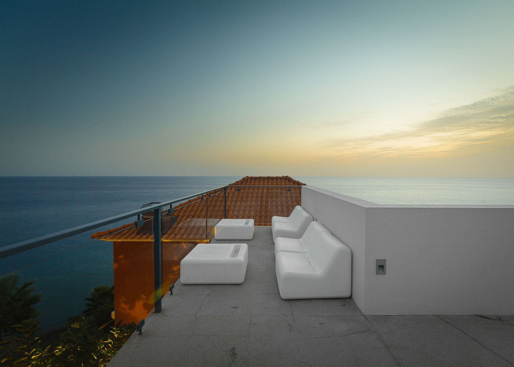 Une terrasse offrant une vue sur la mer, avec un canapé blanc et un toit recouvert de tuiles.