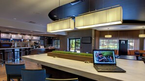A modern hotel lobby with a bar area, seating, and a large screen displaying a video. - Courtyard by Marriott Madison East (Madison)