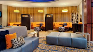 A modern lobby with a sofa, ottoman, and seating area with tables. - Courtyard by Marriott Madison East (Madison)
