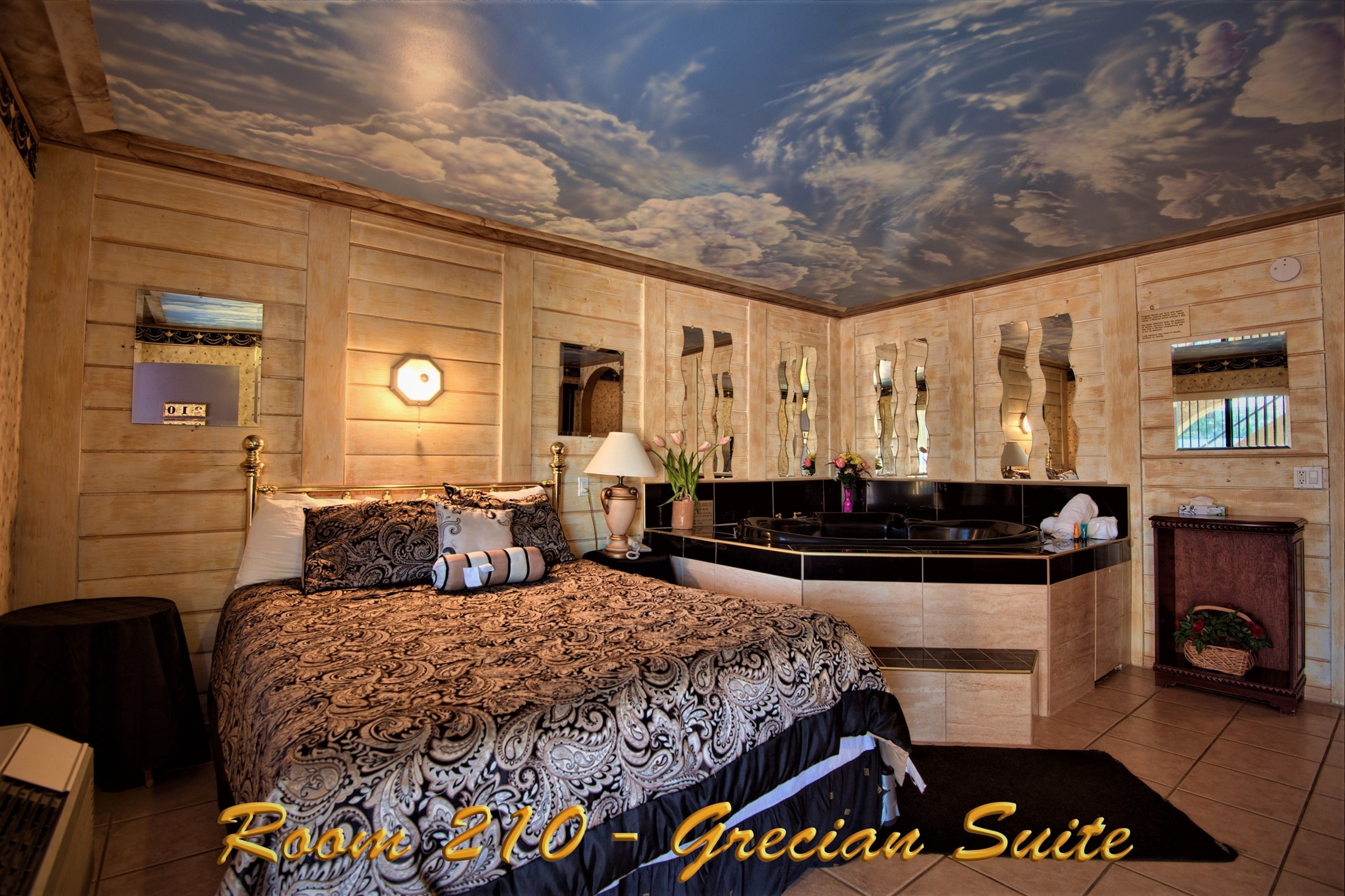 A room with a bed, a vanity, and a ceiling with a cloud design.