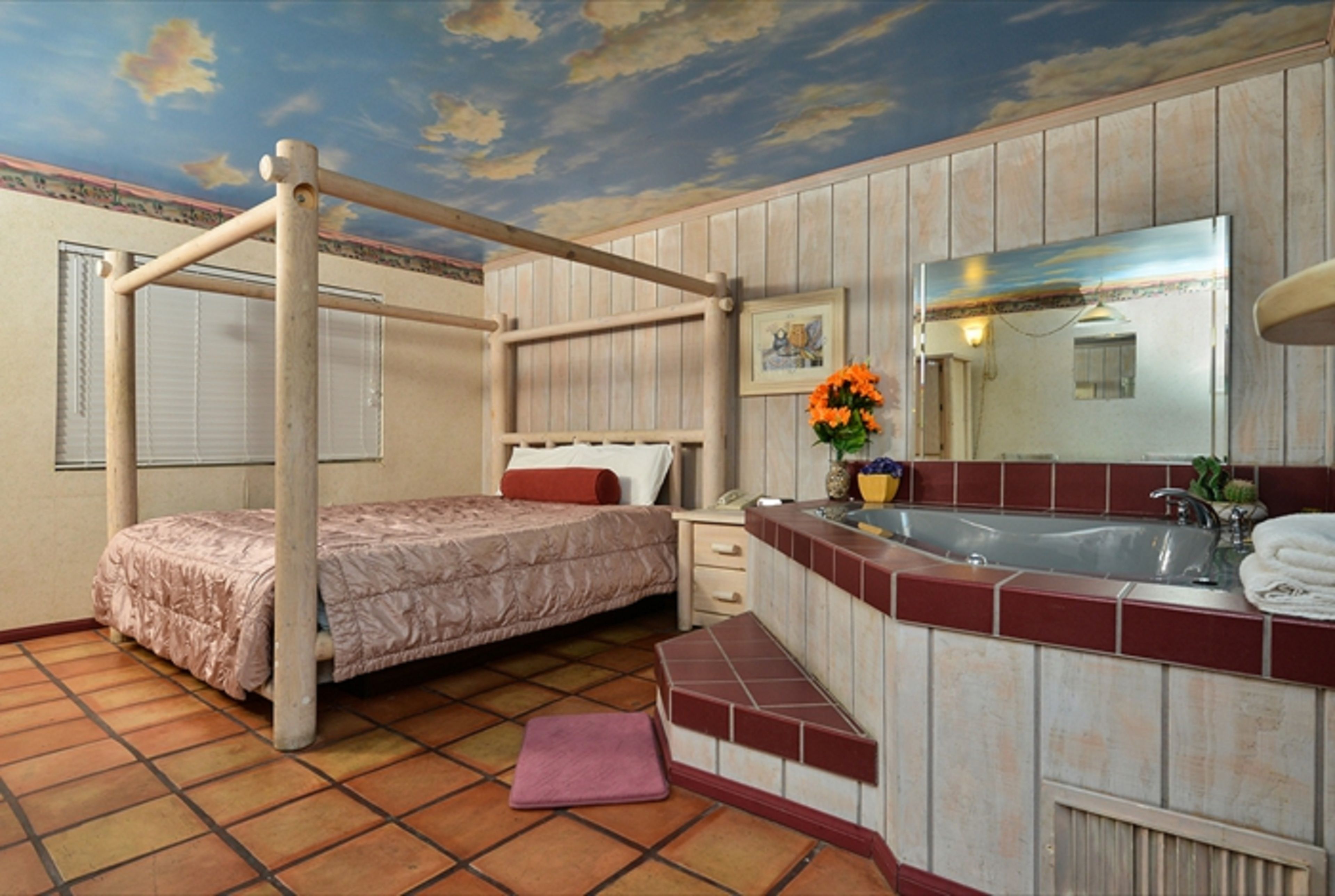 Una stanza con un letto a castello, un bagno con lavandino e specchio, e un pavimento piastrellato.