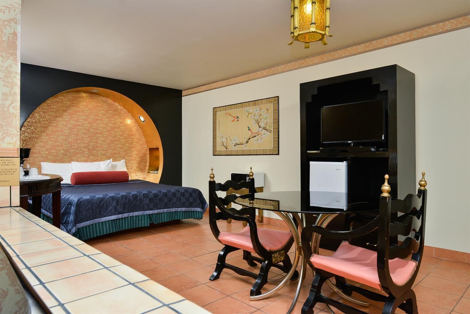 Une chambre d’hôtel comprenant un lit, un bureau avec une chaise, une télévision et un élément décoratif mural.