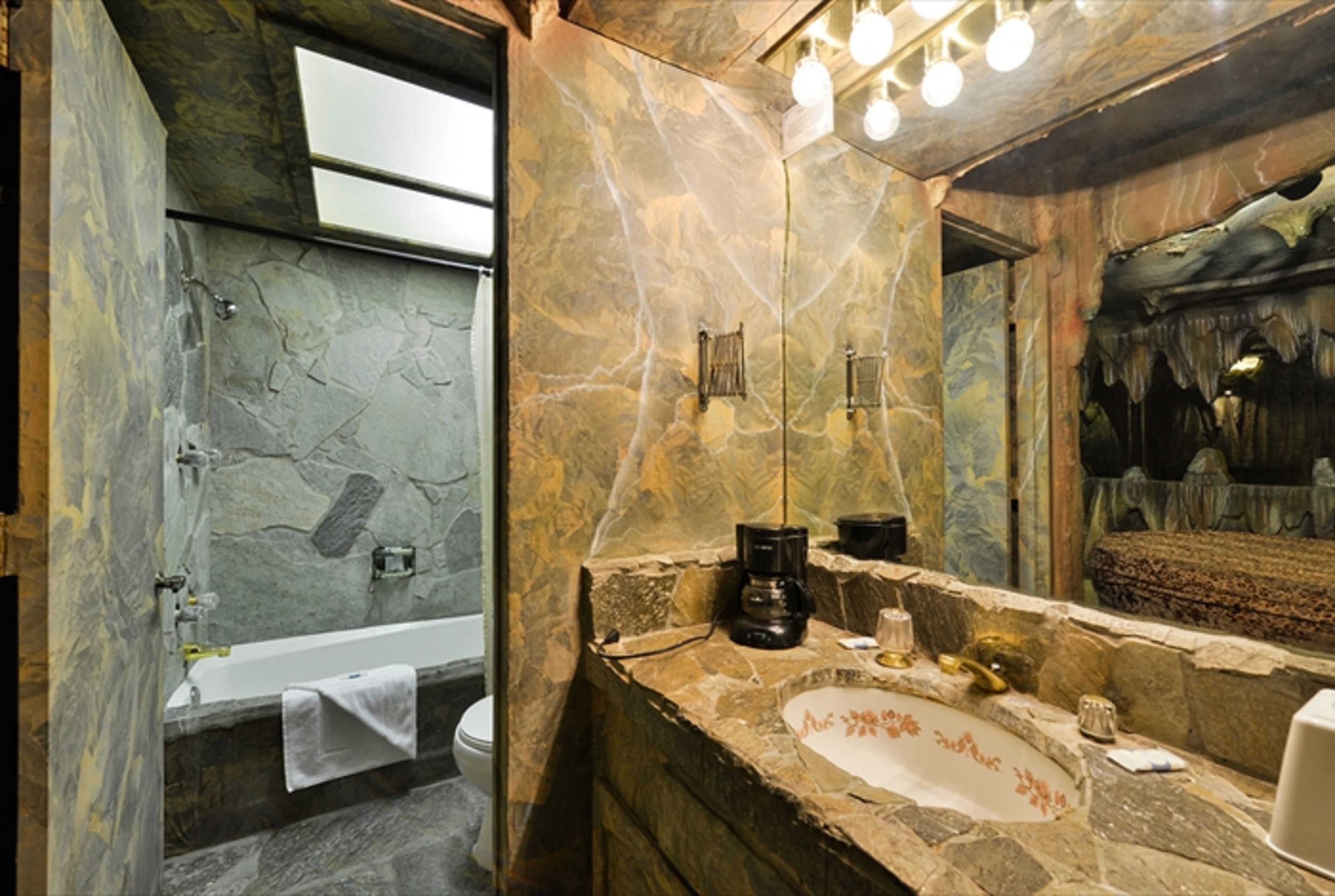 A bathroom with a stone sink, a mirror, and a bathtub.
